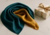 Folded luxury silk scarf in teal and gold beside a ribbon-tied gift box on marble — silk scarf gift styling