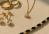 Flat lay of fine jewellery pieces including gold rings, diamond pendant and sapphire bracelet on ivory linen