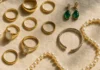Flat-lay arrangement of gold rings, pearl necklaces and gemstone jewellery on cream linen fabric