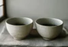Two ceramic bowls on a linen cloth in soft morning light, evoking the calm of mindful tea drinking