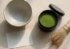 Matcha dovanų rinkinys su bambuko šluotele ir keraminiu dubeniu ant medinio paviršiaus