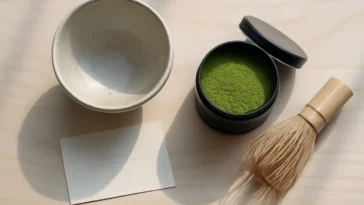 Matcha dovanų rinkinys su bambuko šluotele ir keraminiu dubeniu ant medinio paviršiaus